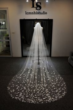 the back of a wedding veil with white flowers on it in front of a building