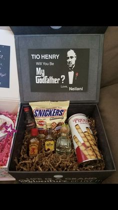 a box filled with snacks and condiments on top of a couch next to a sign