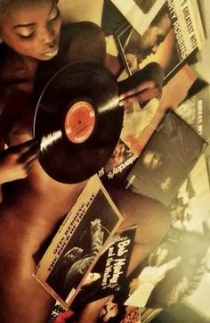 a woman holding a record in her hand while laying on the floor next to other records