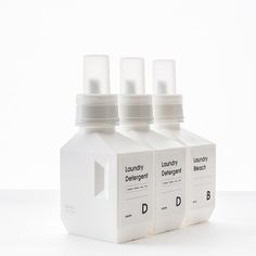 three bottles of liquid sitting next to each other on a white surface with no one in it