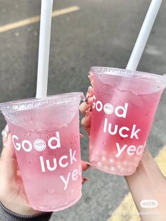 two people holding up plastic cups with good luck and yeah written on the side in front of them