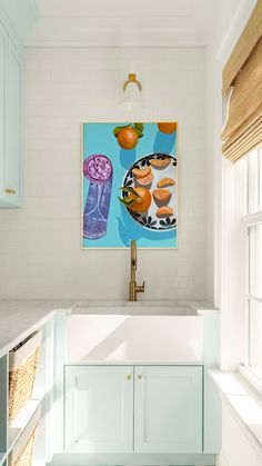 a painting hangs above a kitchen sink with blue cabinets and white countertops in front of it