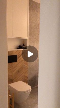 a white toilet sitting inside of a bathroom next to a wooden cabinet and counter top