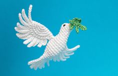 a white bird flying through the air with a green leaf on it's beak