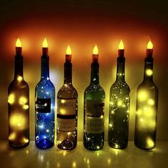 several bottles with lights on them are lined up in front of each other as if they were lit