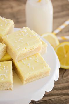 several pieces of cake on a white plate with lemons and milk in the background