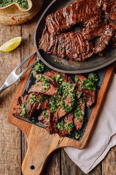 steak and broccoli on a cutting board next to a skillet with tongs