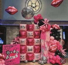 pink and black party decorations on display in front of a mirror with disco balls hanging from the ceiling