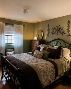 a bedroom with a bed, dresser and mirror on the wall next to it's windows