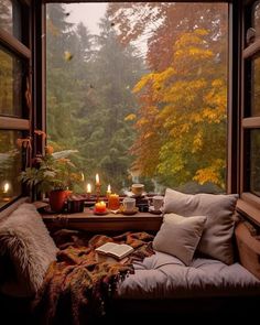 a window seat with candles on it in front of a tree filled forest outside the window