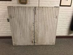 an old metal door is in front of a white brick wall with pictures on it