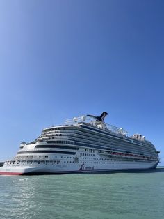 a large cruise ship in the middle of the ocean with clear blue skies above it