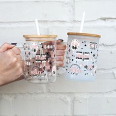 two people holding up cups with straws in them