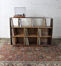 a bookcase with many books on top of it in front of a brick wall