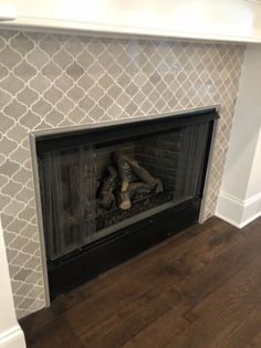 a fireplace with a white and gray wallpaper on the back side, and wood floors