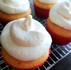 several cupcakes with white frosting sitting on a cooling rack