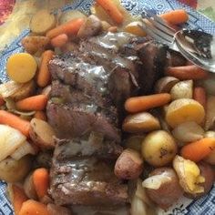 a plate full of meat, potatoes and carrots with a fork on the side