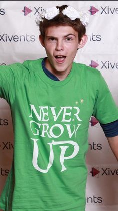 a young man wearing a green t - shirt with the words never grow up on it