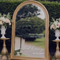 a mirror with flowers on it sitting next to two vases and a sign that says hello friends we're glad you're here