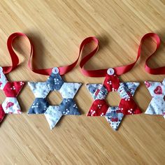 three pieces of fabric are hanging on a table together with red, white and blue ribbons