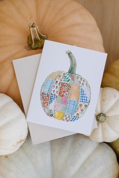 a card with a patchwork pumpkin on it next to other pumpkins and squash