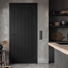 a black door in a gray kitchen next to a counter