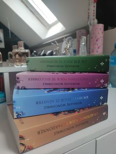 a stack of books sitting on top of a white counter next to a blue bottle