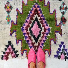 a woman's feet in pink shoes standing on a rug