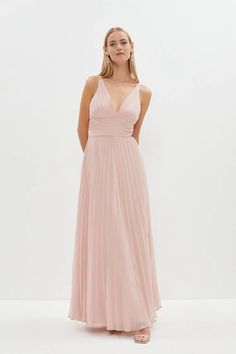 a woman in a long pink dress is standing with her hands on her hips and looking at the camera