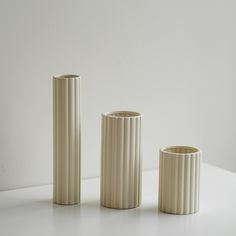 three white vases sitting on top of a table