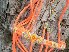 an orange rope with beads on it sitting next to a tree