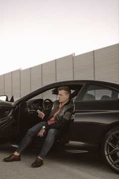 a man sitting in the driver's seat of a car next to another car