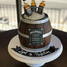 there is a cake made to look like a barrel with three bottles on top and the name jack daniels next to it