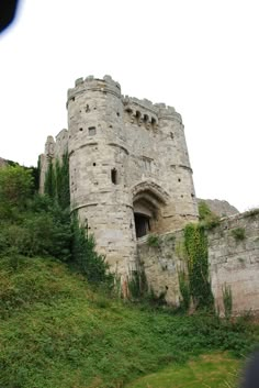 an old stone castle sitting on top of a lush green hillside