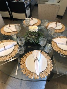 a glass table topped with white plates and silverware covered in gold trimmings