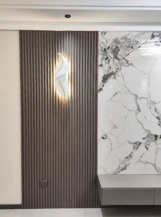 a bathroom with marble walls and flooring next to a wall mounted toilet paper dispenser