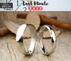 two wedding rings sitting next to each other on top of a wooden table with leaves