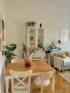 a dining room table and chairs with plants in the corner