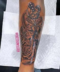 a woman's leg with a butterfly and roses tattoo on it