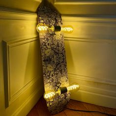 a skateboard that is sitting on the floor next to a wall with some lights