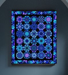 a blue and purple quilt hanging on the wall