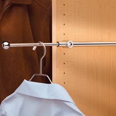 a white shirt is hanging on a metal bar in front of a wooden closet door