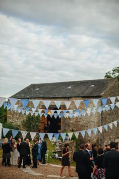 a group of people standing around each other in front of a building with bunting