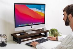 a man sitting in front of a computer on a desk with a keyboard and mouse