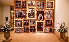 a wall with pictures and lights on it in a hallway next to vases filled with flowers