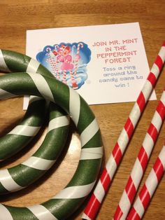 some candy canes are sitting on a table next to a card and paper straws