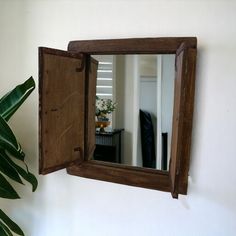 a mirror hanging on the wall next to a potted plant