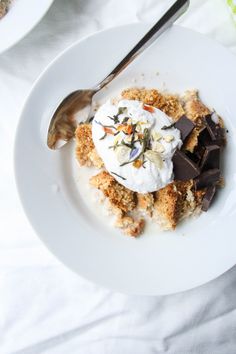 a white plate topped with dessert next to a bowl of whipped cream and spoons