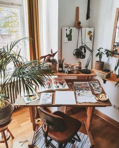 a table with plants and pictures on it in front of a window, next to a potted plant