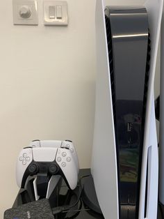 two video game controllers sitting next to each other on top of a table in front of a white wall